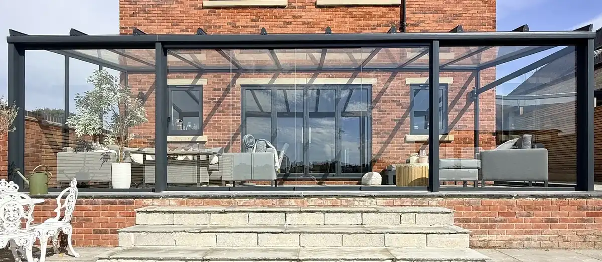 Anthracite glass room with full-height sliding glass walls on a brick house