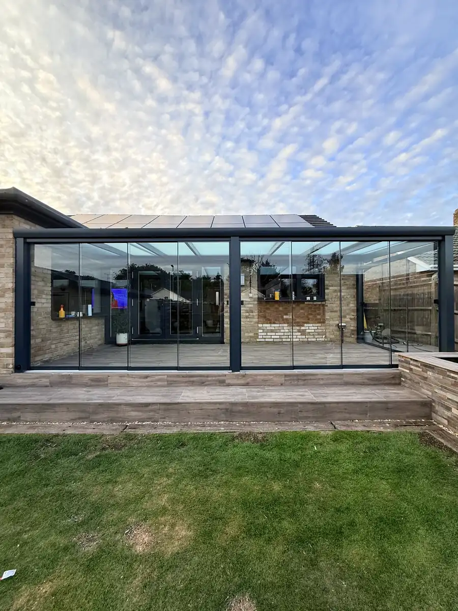 Anthracite glass room across the back of a bungalow in Blackwater, seen from the lawn