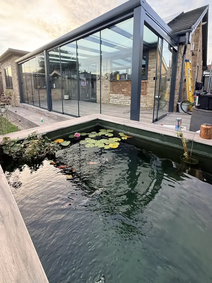 Glass room beside the garden pond, with sliding glass walls on the side