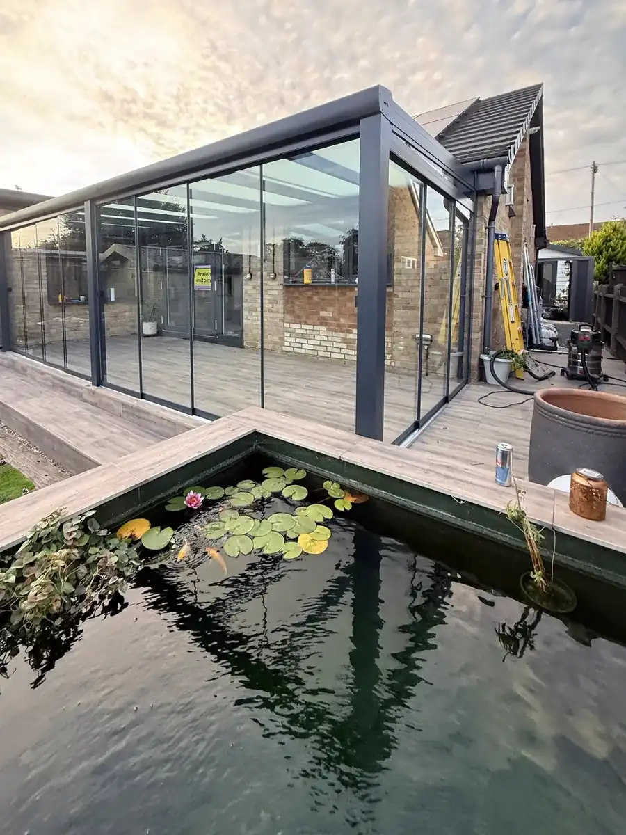 Glass room on the raised terrace next to the pond with water lilies