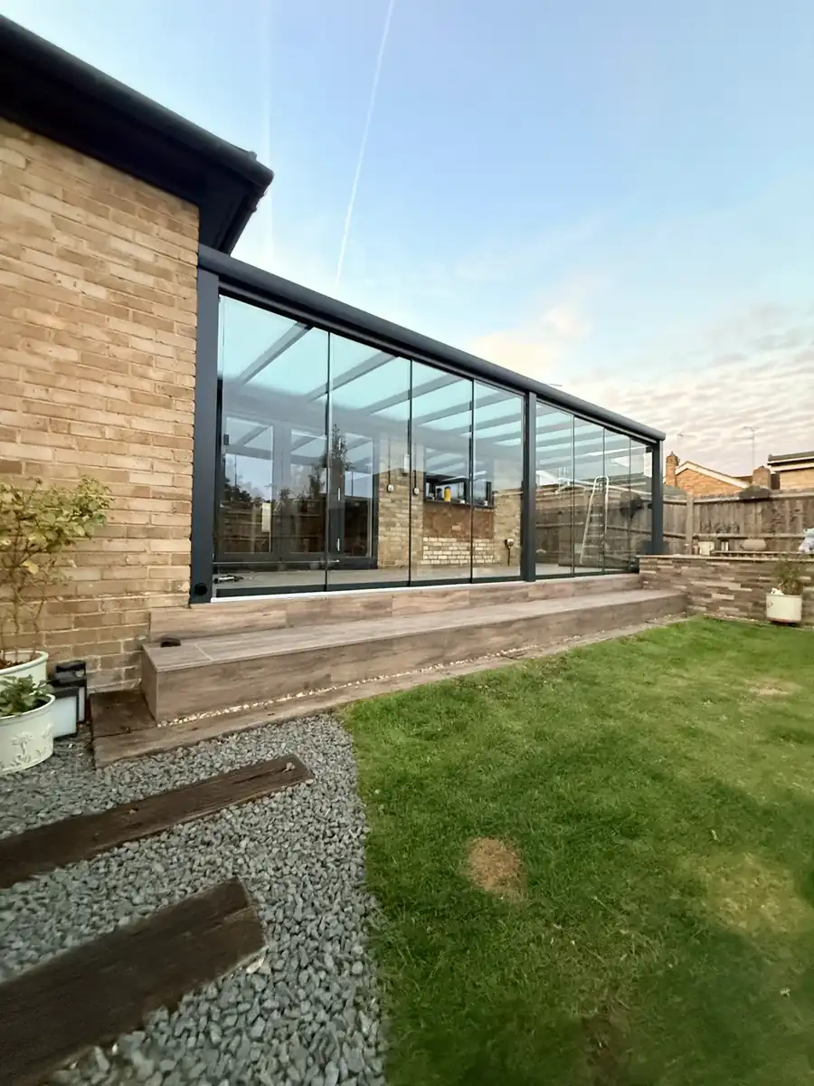 Glass room along the side of the bungalow, with the lawn in front