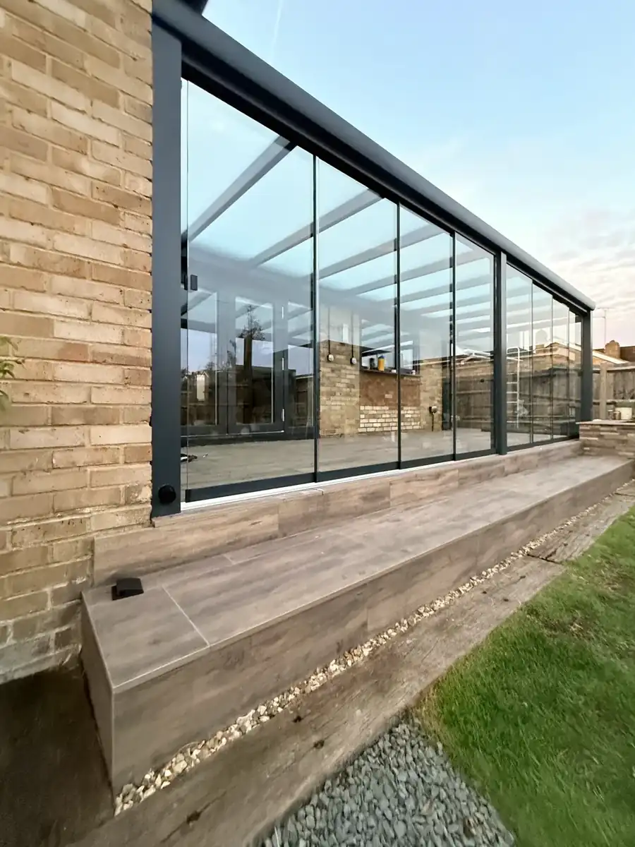 Sliding glass walls and anthracite frame on the raised terrace