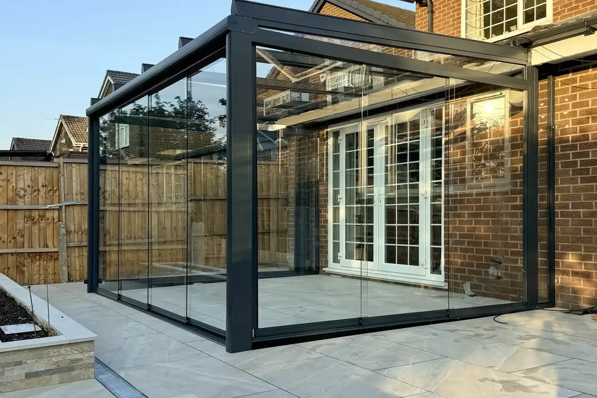Anthracite glass room with sliding glass walls on a raised porcelain patio in Bolton