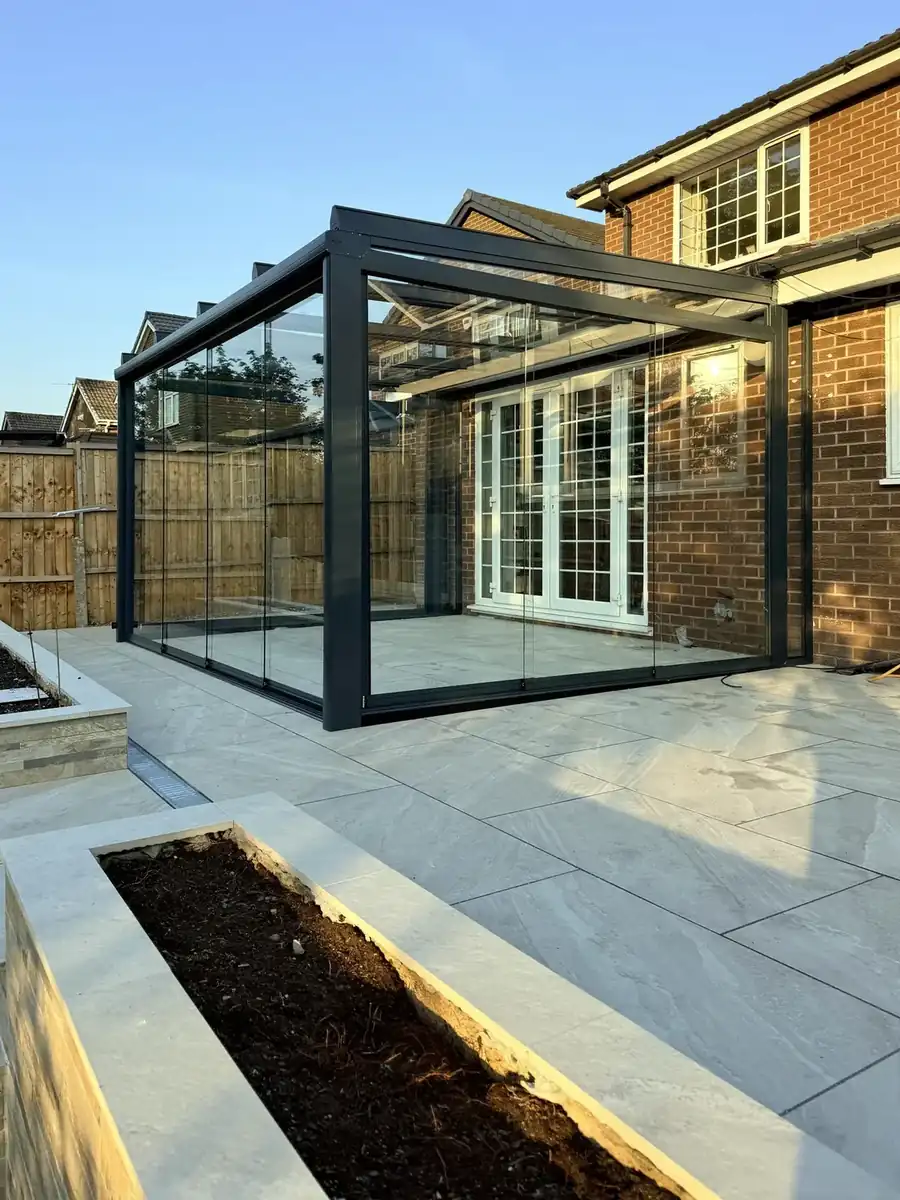 Anthracite glass room with sliding glass walls on a raised porcelain patio in Bolton