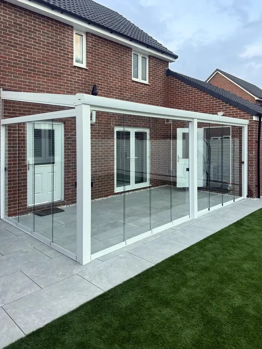 White glass room with sliding glass walls across the back of a brick house in Oxford