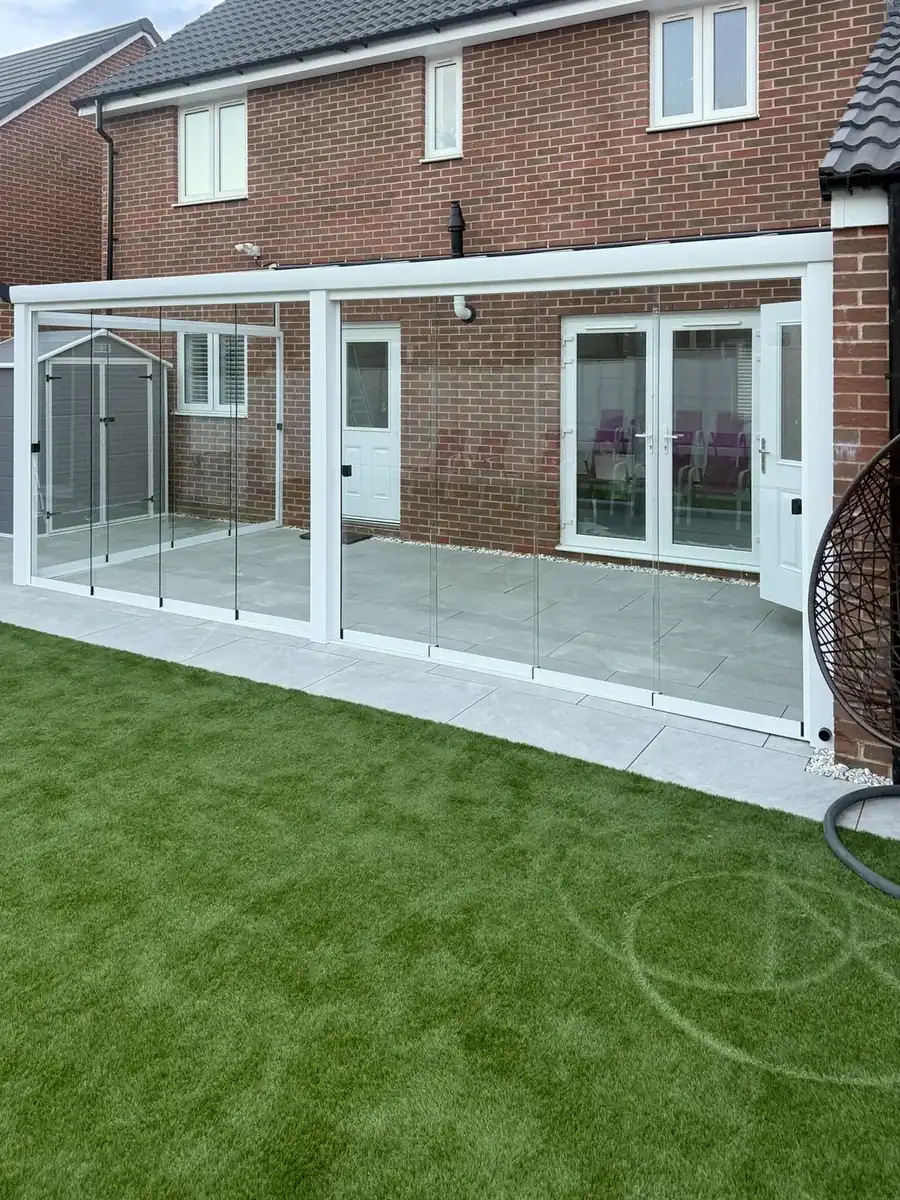 White glass room from the garden corner, spanning the full width of the house
