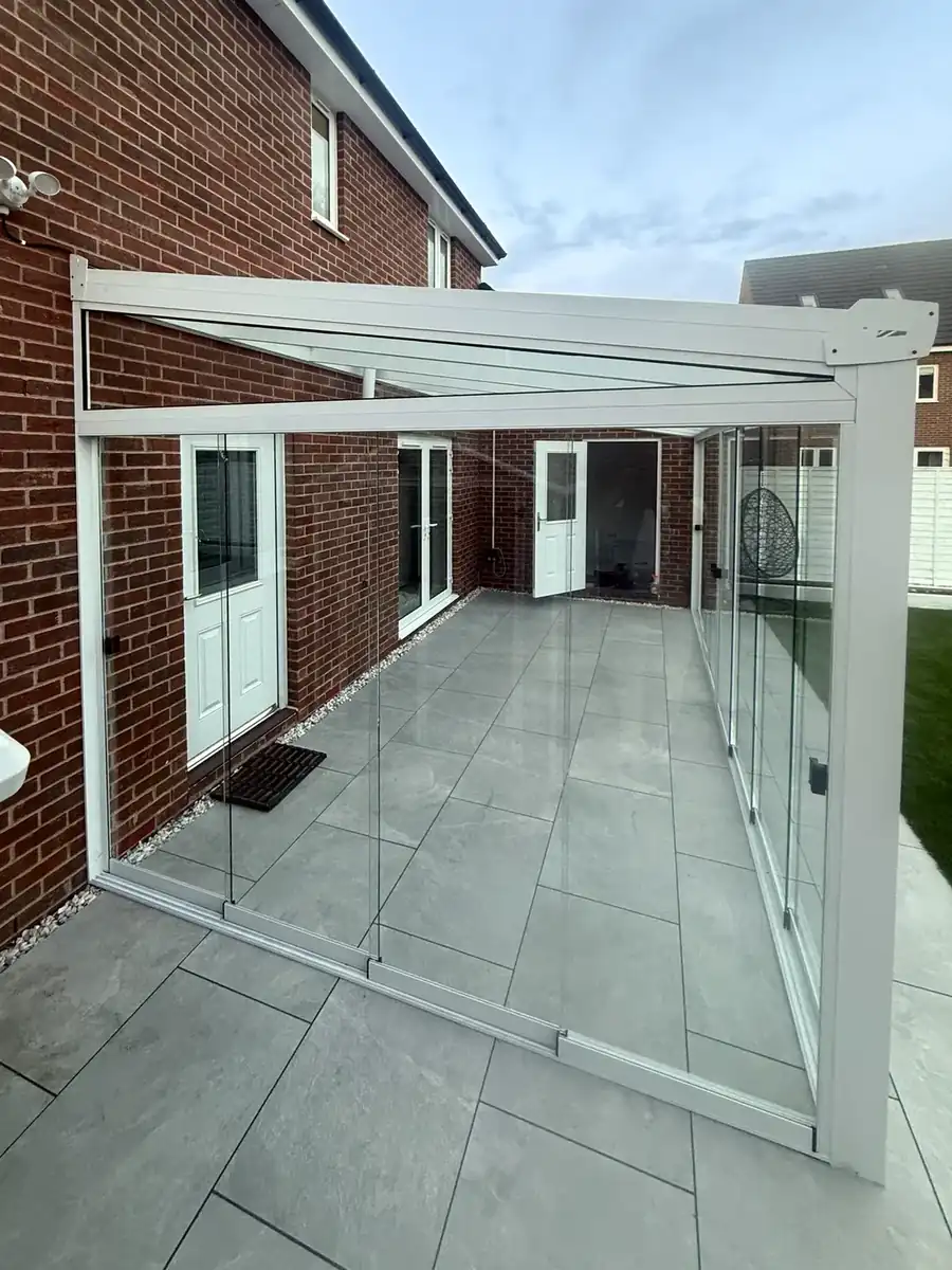 Side view along the white glass room and the sliding glass walls on the paving